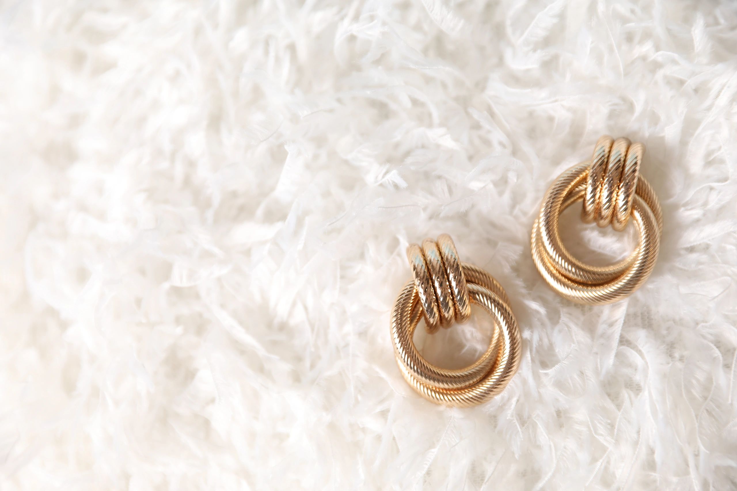 Gold earrings displayed on feathers